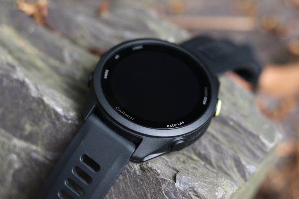 Black Garmin Forerunner 70 resting on stone outdoors, with its screen switched off